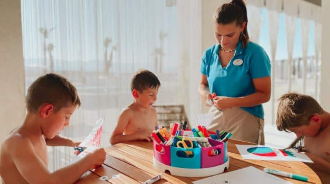 resort worker doing arts and crafts with children
