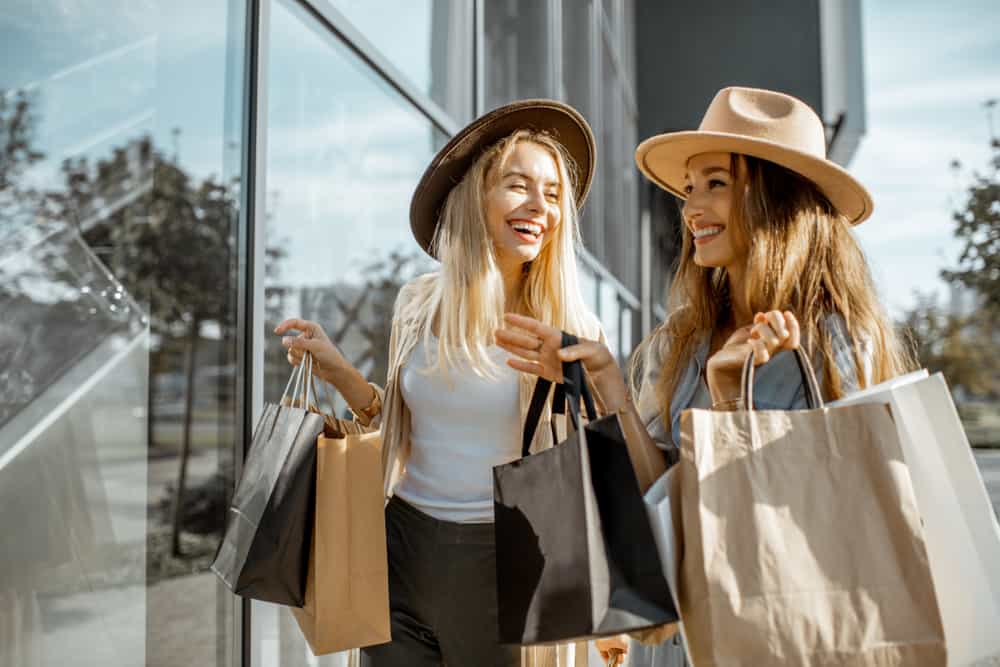 2 girls holding shopping bags and talking